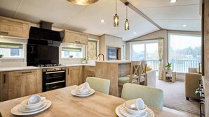 Una cocina moderna con armarios de madera, un comedor con una mesa preparada para cuatro personas y vistas de la ciudad a través de amplias ventanas.
