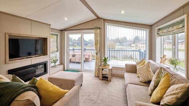 Amplia sala de estar con una televisión de pantalla plana, chimenea, un conjunto de sofás y ventanas grandes que ofrecen vistas al exterior.