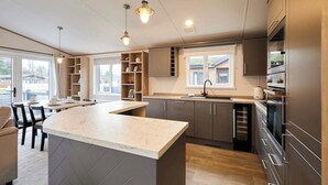 Una cocina moderna con una isla central, estantes empotrados y un amplio ventanal.