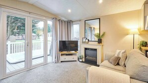 Ein Wohnzimmer mit Fernseher, Kamin, Sofa und einer Glasschiebetür, die auf einen Balkon führt.