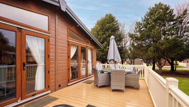 Eine Holzterrasse mit Whirlpool, Korbmöbeln und einer überdachten Patio.