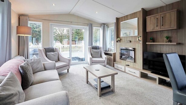 A modern living room with a sofa, armchairs, a coffee table, a TV, and a fireplace. - Host & Stay | Lakeshore Lodge (Pocklington)
