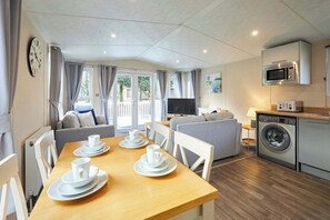 Een functionele woonruimte met een eethoek, bank, televisie, wasmachine en kitchenette.