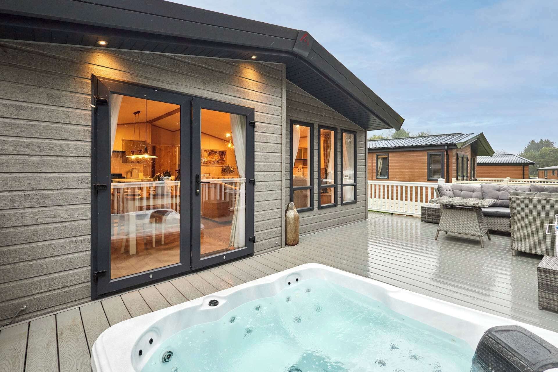Eine moderne Terrasse im Freien mit Whirlpool, Holzdeck und Essbereich mit Gartenmöbeln.
