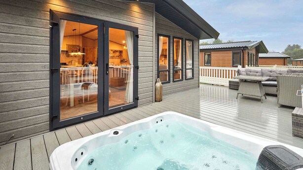 Eine moderne Terrasse im Freien mit Whirlpool, Holzdeck und Essbereich mit Gartenmöbeln.