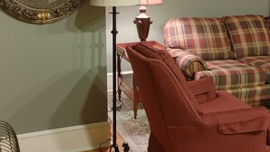 Una sala de estar con un sofá rojo, un tapete estampado, una lámpara de pie y un espejo en la pared.
