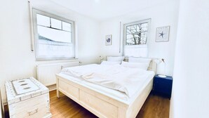 Et soveværelse med en træseng, et kommode, et natbord og et vindue med udsigt til en bygning.