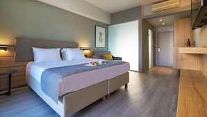 Une chambre moderne avec un grand lit, des tables de chevet, un banc en bois et un coin cuisine.