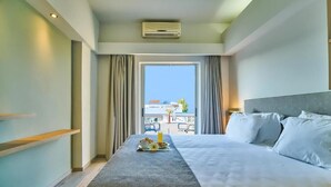 Une chambre d’hôtel avec un lit, une petite table pour le petit-déjeuner, une fenêtre et un balcon avec vue.