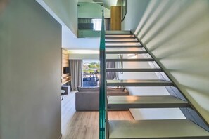 A modern interior with a staircase leading to a balcony. - Bella Pais Hotel (Maleme)