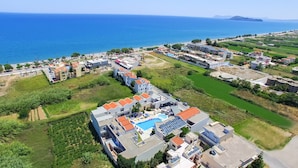 Vue aérienne d’un quartier résidentiel situé sur la côte, avec une piscine, des espaces verts et une vue sur la mer.