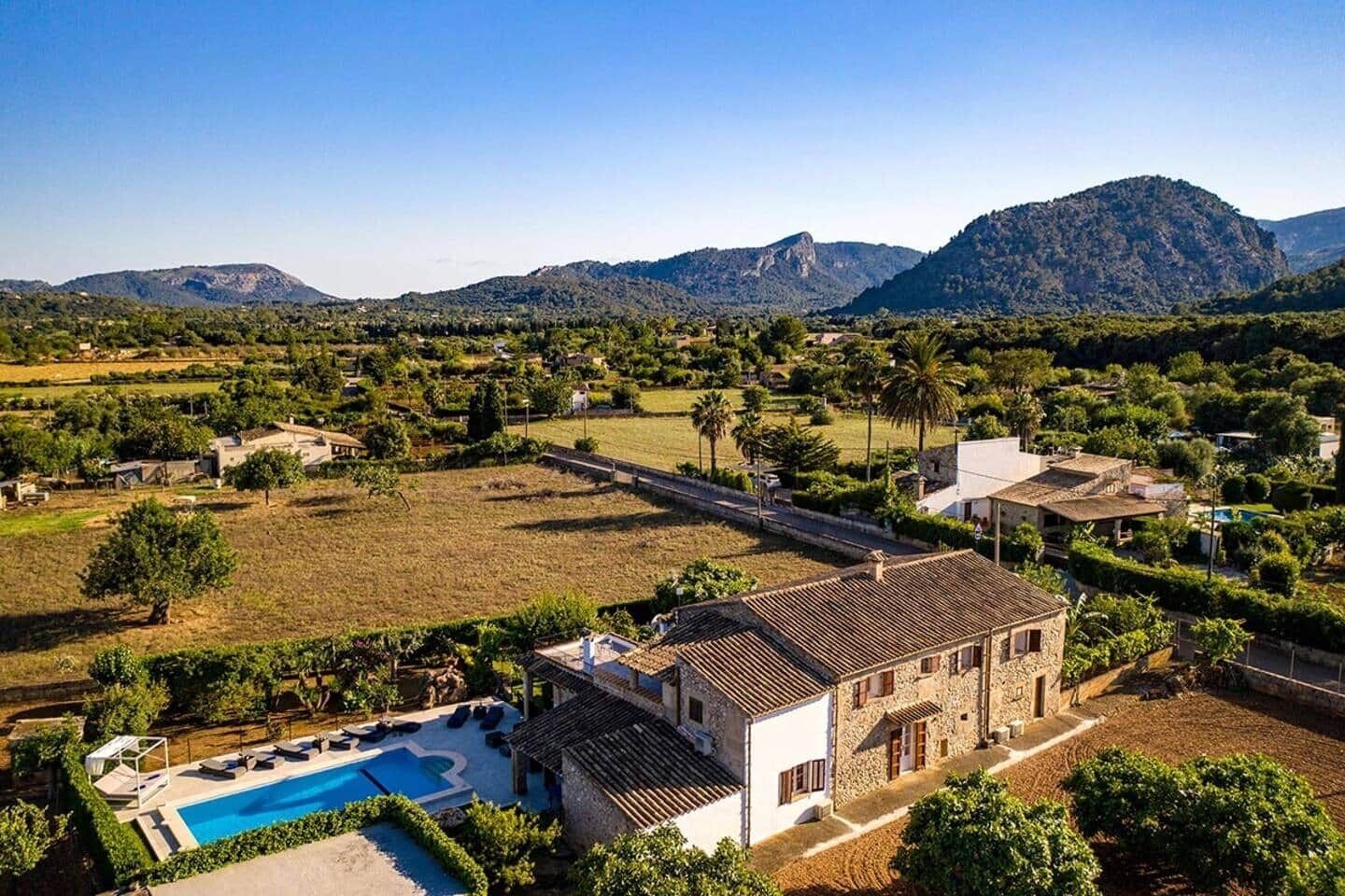 Eine Villa mit Swimmingpool, umgeben von Feldern und Bergen.