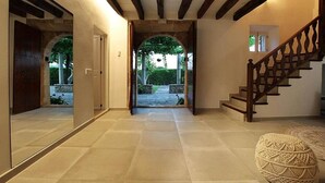 Ein Flur mit einer Holztreppe, einem großen Spiegel und Blick auf einen Garten.