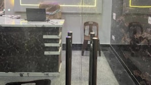 A reception area with a marble counter, a laptop, framed pictures on the wall, and a 'RECEPTION' sign. - Shri Bhagat Ji Seva Dham (Vrindavan)