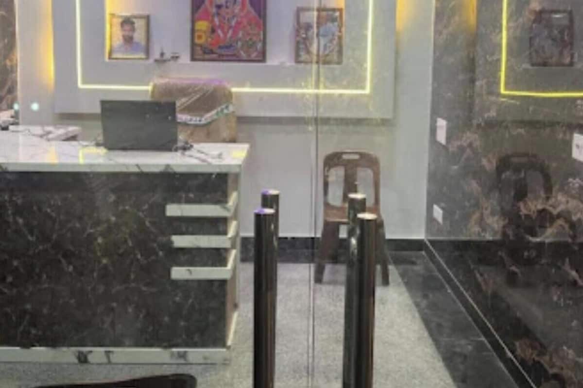 Zona de recepción con mostrador de mármol, una computadora portátil, cuadros enmarcados en la pared y un cartel que dice 'RECEPTION'.