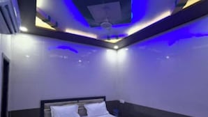 A modern bedroom with a bed, dark walls, and blue ambient lighting. - Shri Bhagat Ji Seva Dham (Vrindavan)
