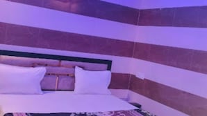 A bedroom with a bed, a ceiling fan, and striped walls. - Shri Bhagat Ji Seva Dham (Vrindavan)