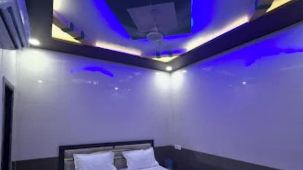 A modern bedroom with a bed, dark walls, and blue ambient lighting. - Shri Bhagat Ji Seva Dham (Vrindavan)