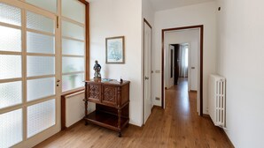 A hallway with wooden flooring, a radiator, a wooden cabinet, and a door with frosted glass panels. - Welcome to "Casa Al Lago" on Lake Iseo (Sulzano)