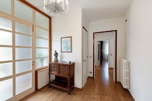 A hallway with wooden flooring, a radiator, a wooden cabinet, and a door with frosted glass panels.