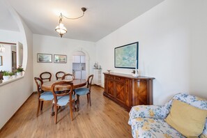 A dining area with a wooden table and chairs, a cabinet, and a sofa with floral upholstery.