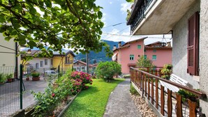 A narrow pathway leading to a building with a wooden fence and potted plants. - Welcome to "Casa Al Lago" on Lake Iseo (Sulzano)