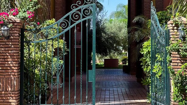 A gated entrance with a brick archway leading to a pathway. - 🌴  Chic & Modern Apartment in the Heart of Hivernage – Pool & Premium Comfort (Marrakech)