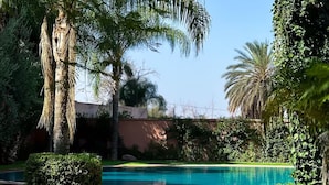 A swimming pool surrounded by lush greenery and palm trees. - 🌴  Chic & Modern Apartment in the Heart of Hivernage – Pool & Premium Comfort (Marrakech)