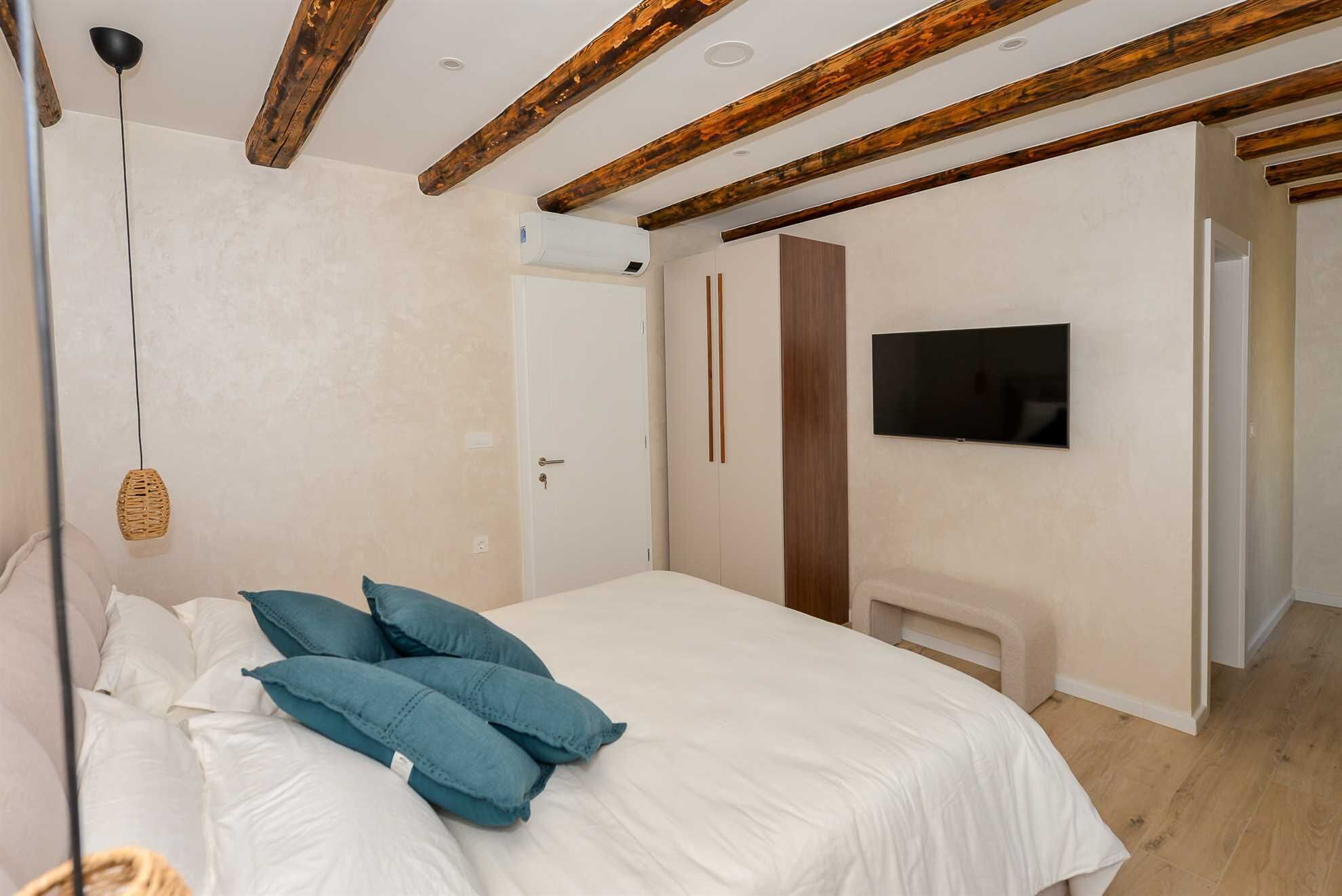 Un dormitorio con cama, almohadas, televisor y chimenea.