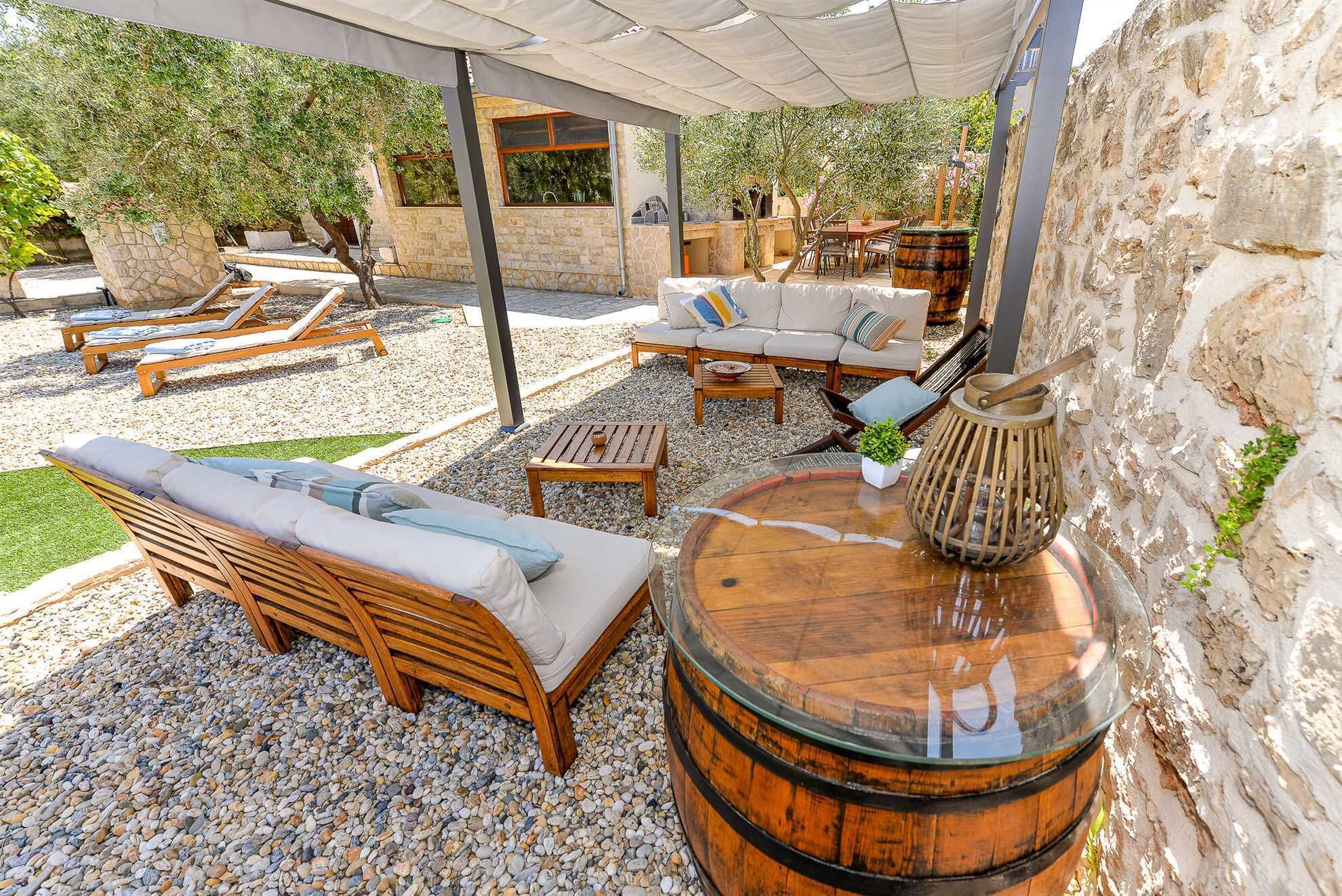 An outdoor seating area with wooden furniture, a stone wall, and a rustic barrel centerpiece.