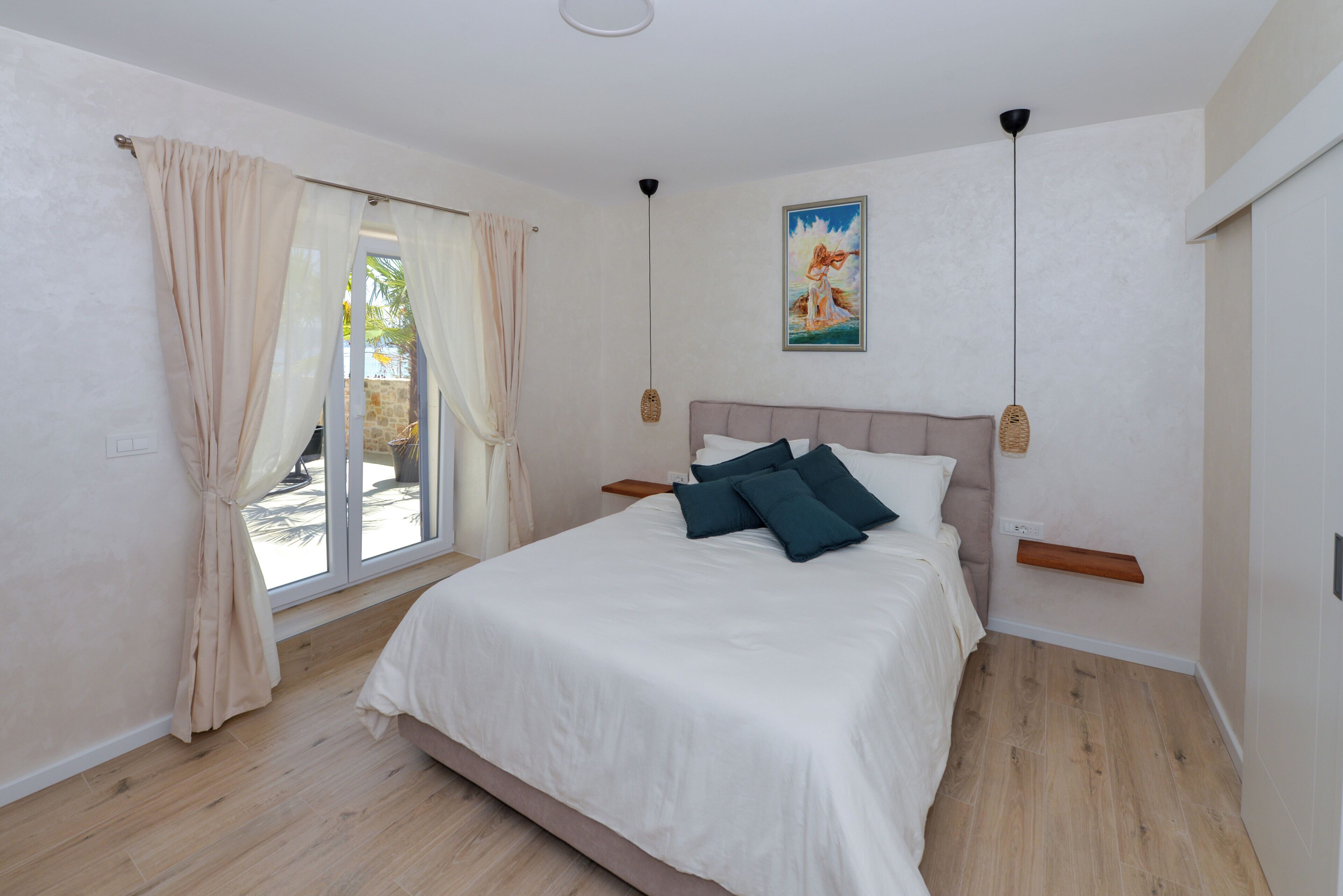 Un dormitorio con cama, cortinas, un cuadro y una lámpara en el techo.