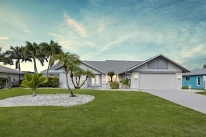 A residential house with a well-maintained lawn, a driveway, and a garage. - Nautical Dream Gulf Access Home (Cape Coral)