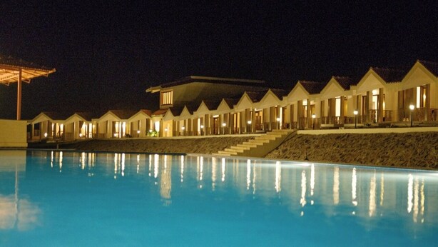 Une série de chambres d’hôtel avec une piscine en premier plan.