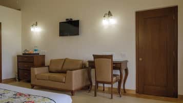 Una habitación de hotel con cama, sofá, sillón, escritorio, televisor y puerta.