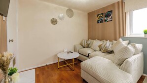 Una sala de estar con un sofá, una mesita redonda y platos decorativos en la pared.