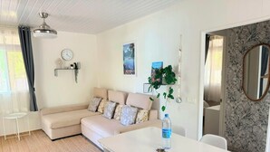 Een moderne woonkamer met een bank, een eettafel en een klok aan de muur.