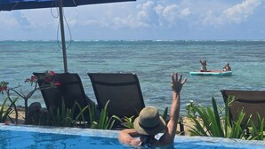 Une vue depuis le bord de la piscine, avec une vue dégagée sur l’océan et une personne dans l’eau.