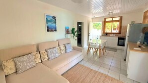 Un salon avec un canapé, un coin repas avec une table et des chaises, et une cuisine équipée d’un réfrigérateur et d’une cuisinière.