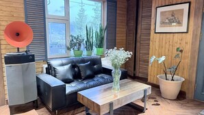 A modern living room with a black leather sofa, a wooden coffee table, and a vintage record player. - Big Sky Lodge (Ulaanbaatar)