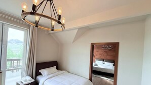 A bedroom with a bed, a nightstand, a wooden headboard, a built-in bench, and a view of the outdoors. - Big Sky Lodge (Ulaanbaatar)