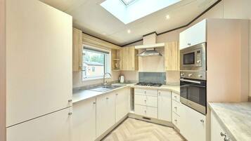 A compact kitchen with a skylight, built-in oven, and a window overlooking a residential area.