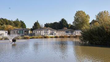 A residential area with houses along a water body, surrounded by trees.
