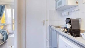 Una cucina compatta con forno a microonde, macchina del caffè e un piccolo lavandino.