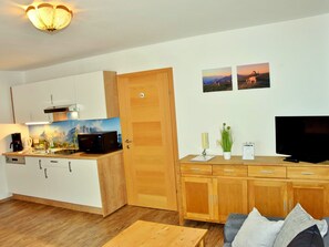 A compact living space with a kitchenette, a flat-screen TV, a sofa, and a coffee machine. - Rosskopf by Interhome (Wildschönau)