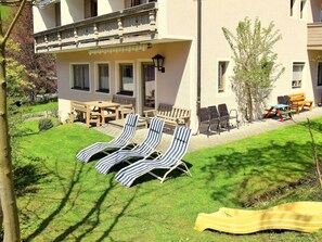 A hotel with a patio area featuring sun loungers, a wooden table, and chairs. - Rosskopf by Interhome (Wildschönau)