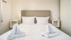 A neatly made bed with two pillows, two bedside tables with lamps, and towels folded on the bed. - Owl's Nest - Wenningstedt-Braderup (Sylt) (Wenningstedt-Braderup (Sylt))