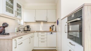A modern kitchen with white cabinetry, a built-in oven, and a coffee maker. - Owl's Nest - Wenningstedt-Braderup (Sylt) (Wenningstedt-Braderup (Sylt))