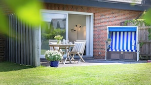 A patio with a table and chairs, a blue and white striped chair, and a potted plant. - Owl's Nest - Wenningstedt-Braderup (Sylt) (Wenningstedt-Braderup (Sylt))