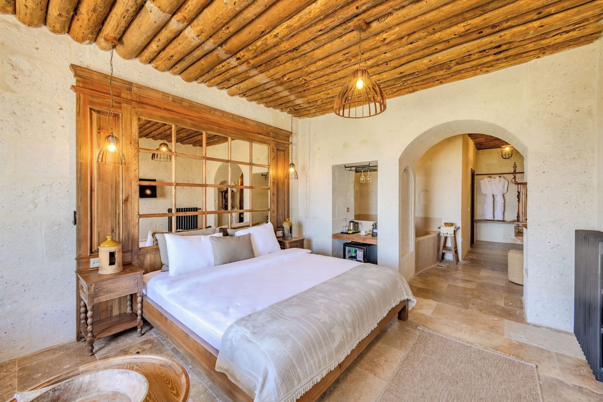 A bedroom with a large bed, wooden headboard, and a wooden ceiling.
