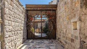Een stenen poort met de tekst 'TOL OF CAPPADOCIA', die uitkomt op een binnenplaats met een fontein.